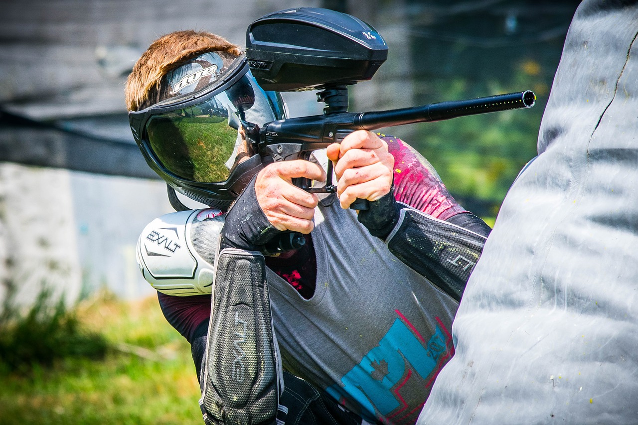 Man wearing a helmet aiming a paintball gun