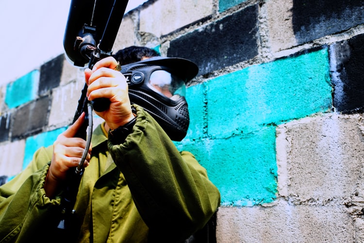 man in green jacket holding paintball gun